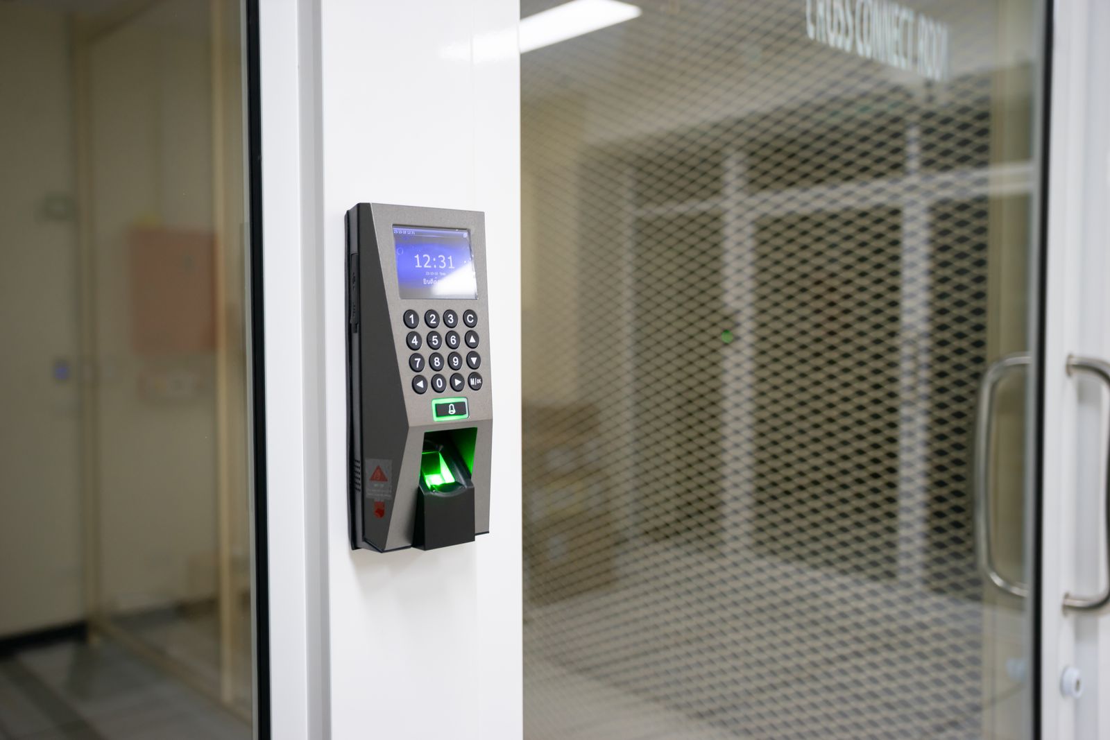 Door keypad with a fingerprint reader beside a glass entrance.